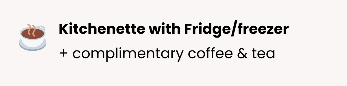 A sign on a kitchen wall advertising a kitchenette with a fridge/freezer, offering complimentary coffee and tea, with a small steaming cup icon.