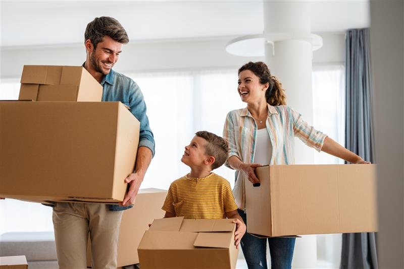 Couple and child carrying moving boxes