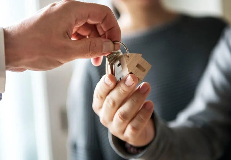Hand passing house keys to another hand