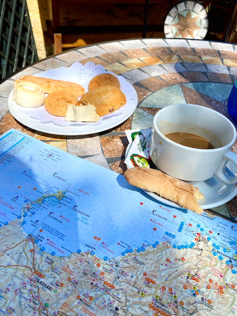 A table with a plate of assorted cookies, a cup of coffee, and a map of Japan.