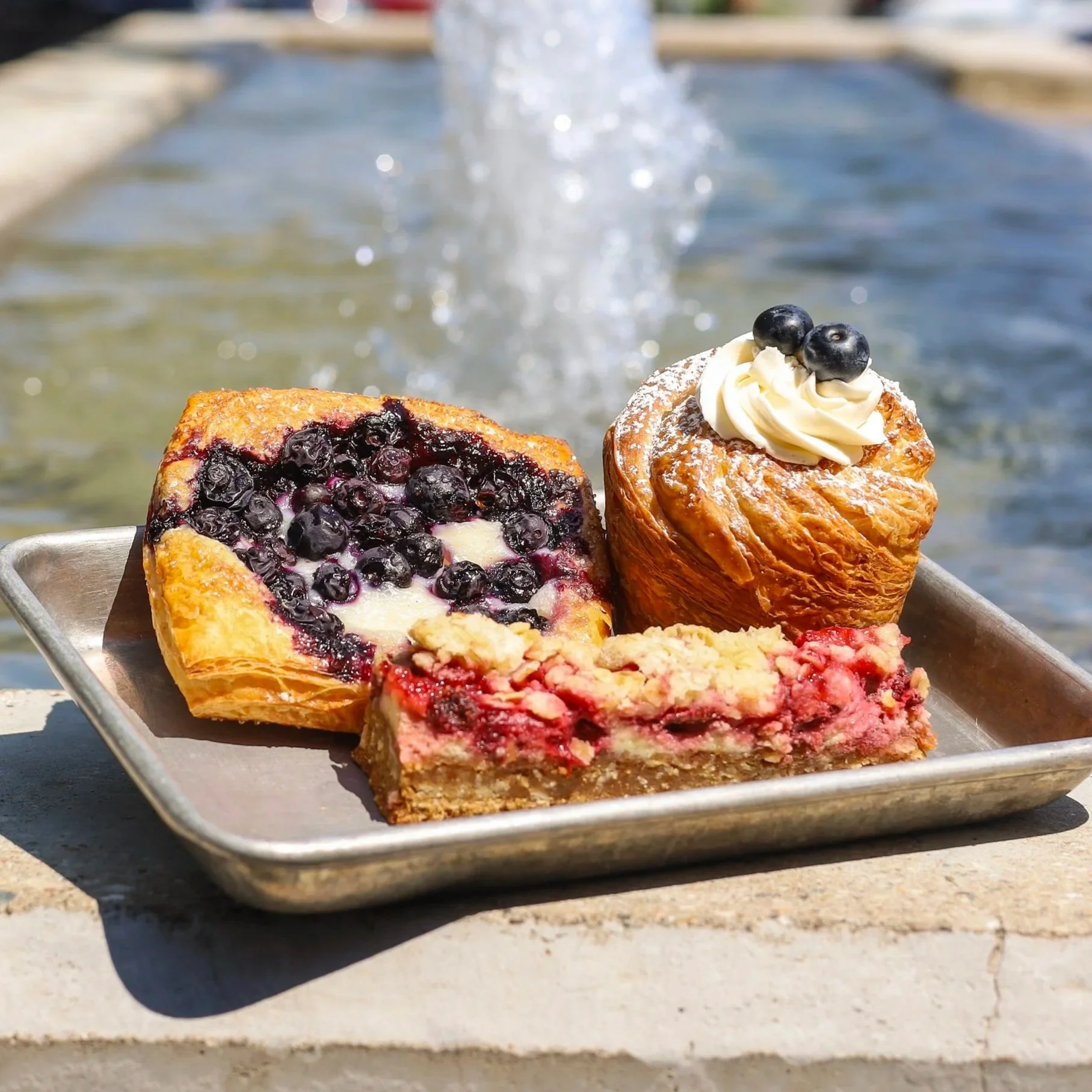 Fruit pastries sitting on a table with green grass in the background.