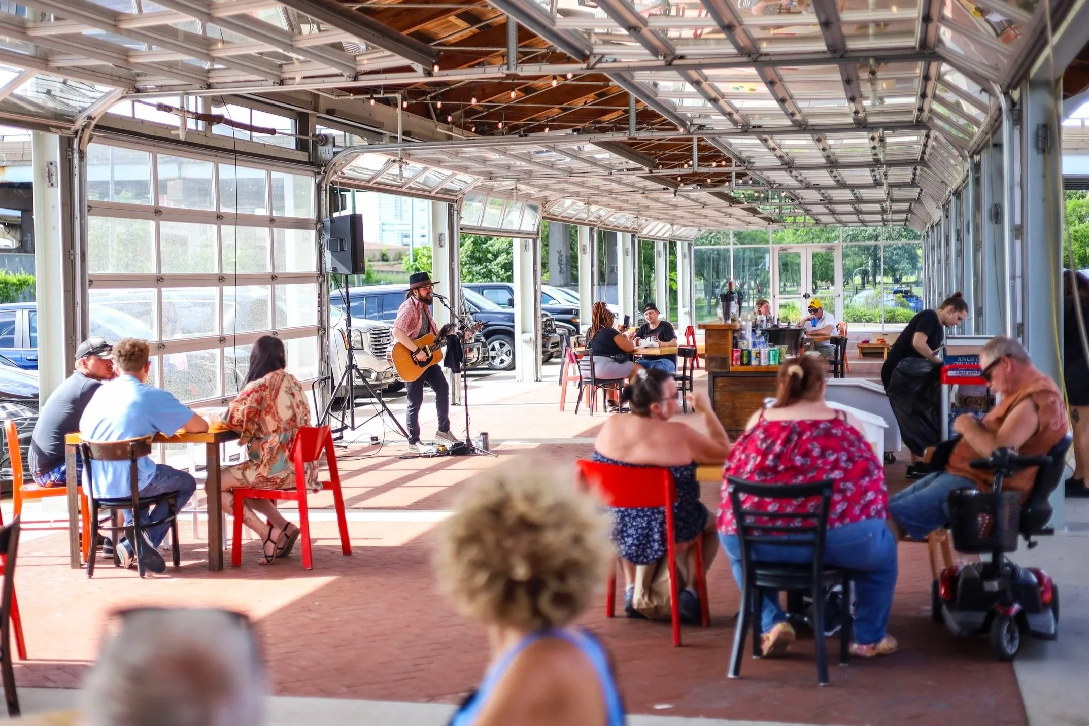 A guitarist performing live on a sunny patio at the downtown market