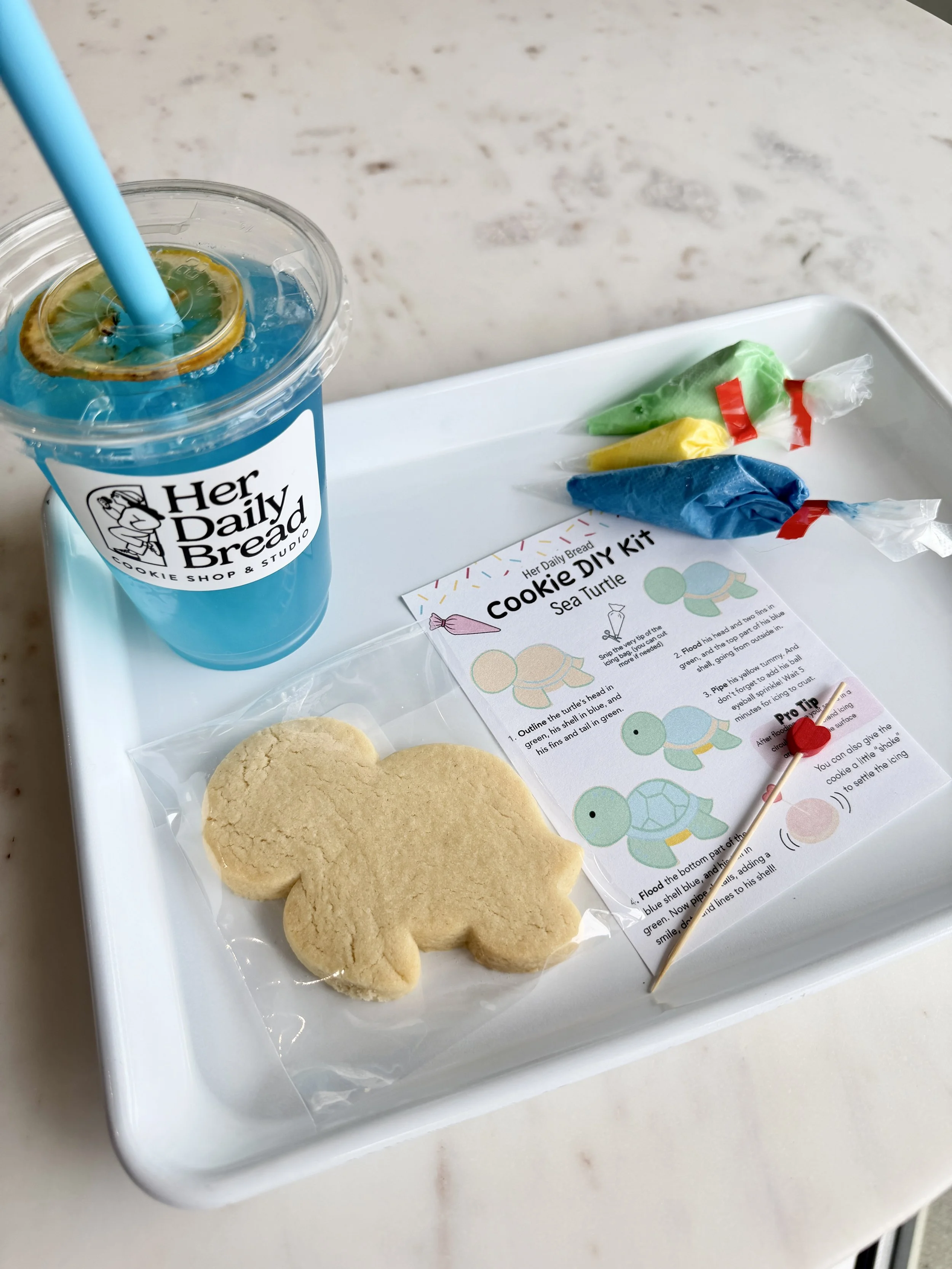 A blue beverage with a DIY cookie kit on a marble surface.