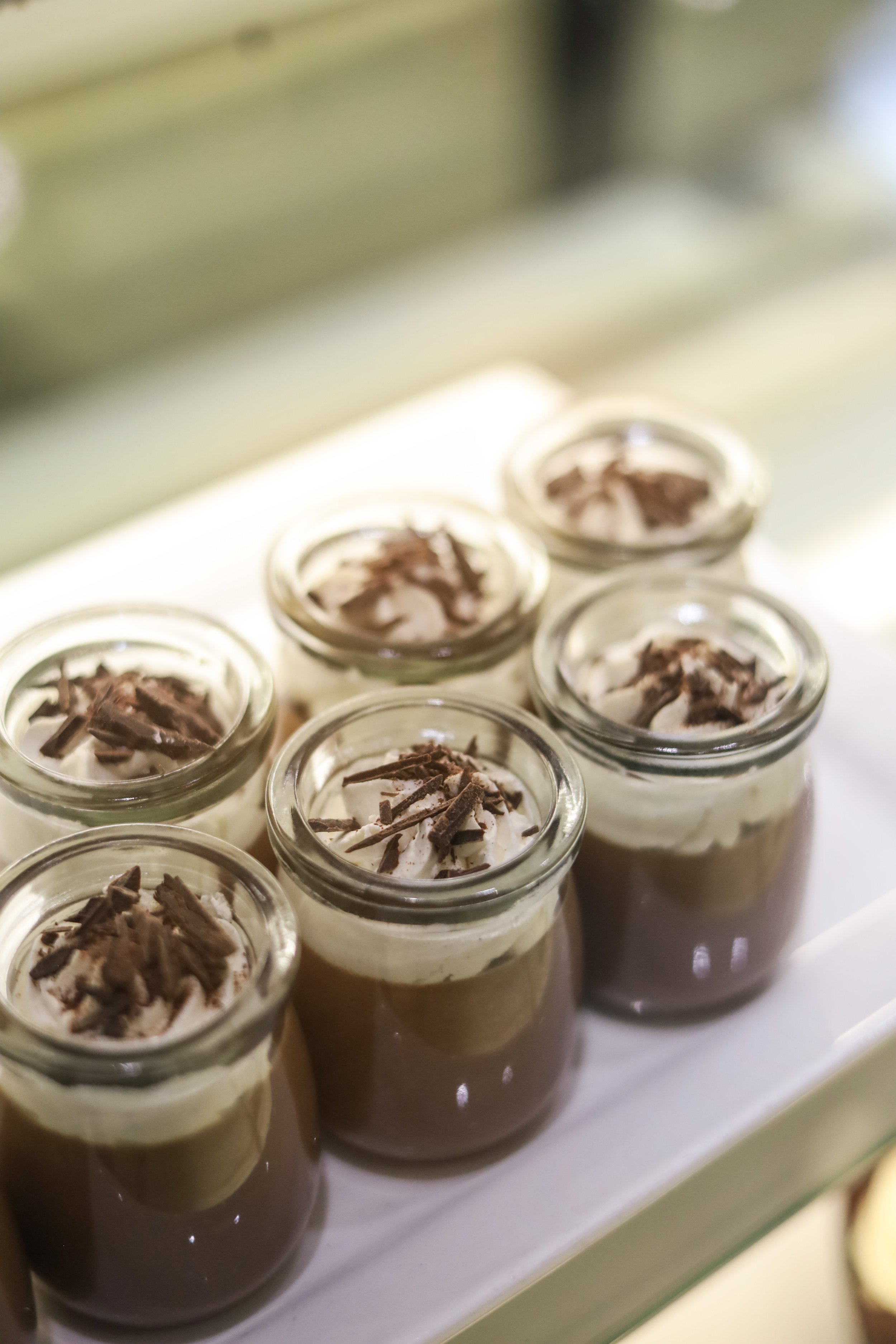Small glass jars filled with layered chocolate mousse topped with whipped cream and chocolate shavings.