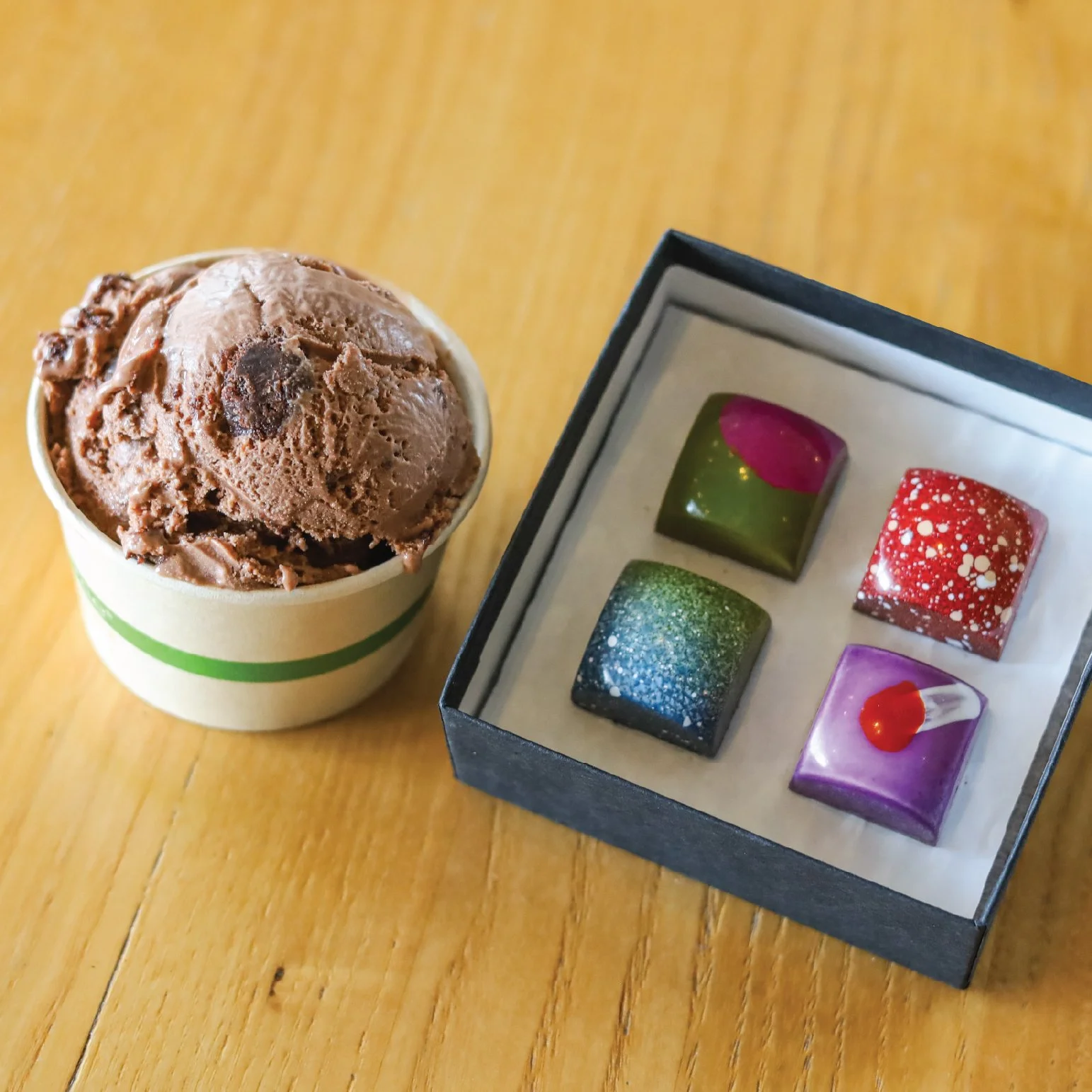 A scoop of chocolate ice cream and a small box of chocolate bon bons.