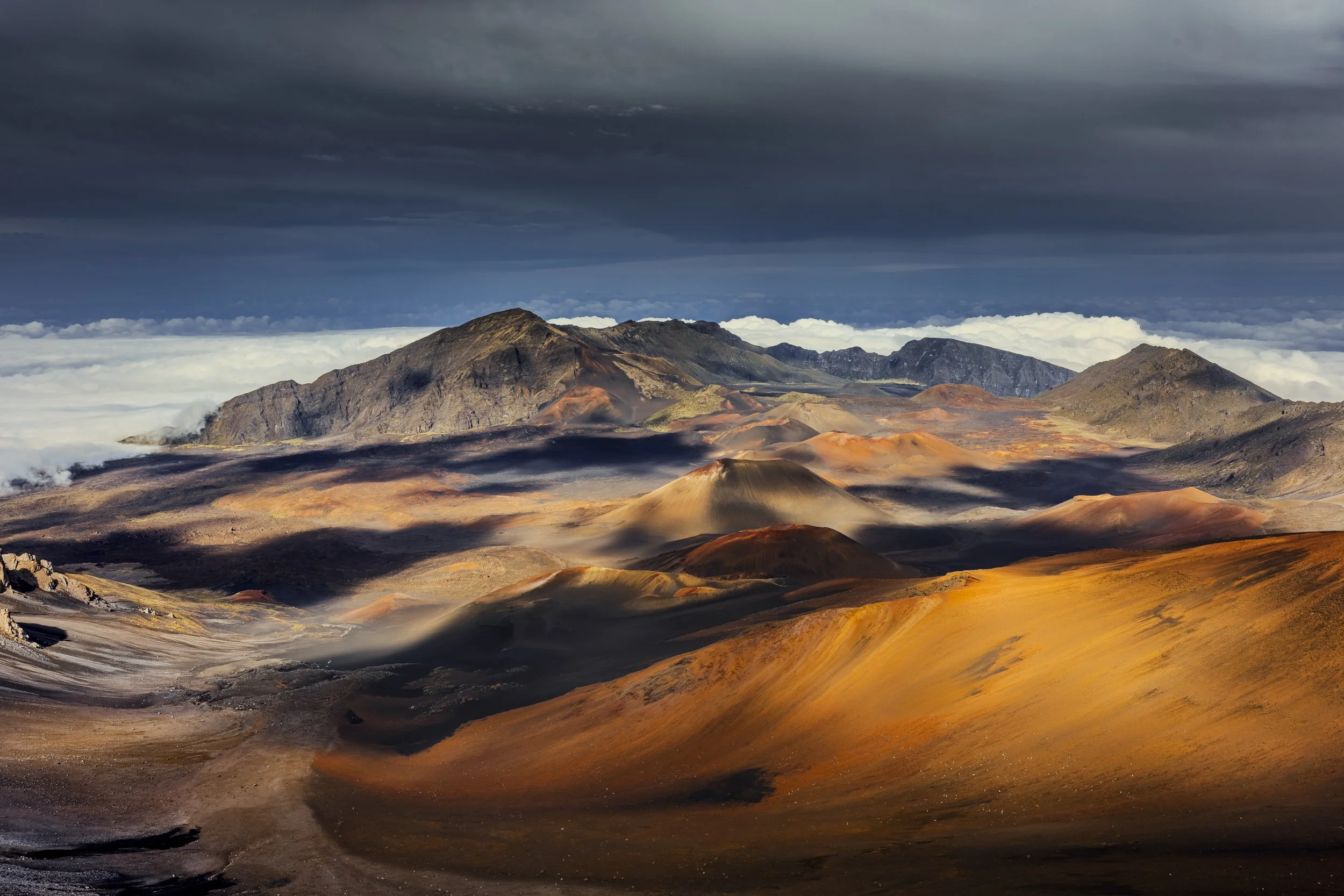 A volcanic landscape with mountains, colorful volcanic rocks, and a cloudy sky.