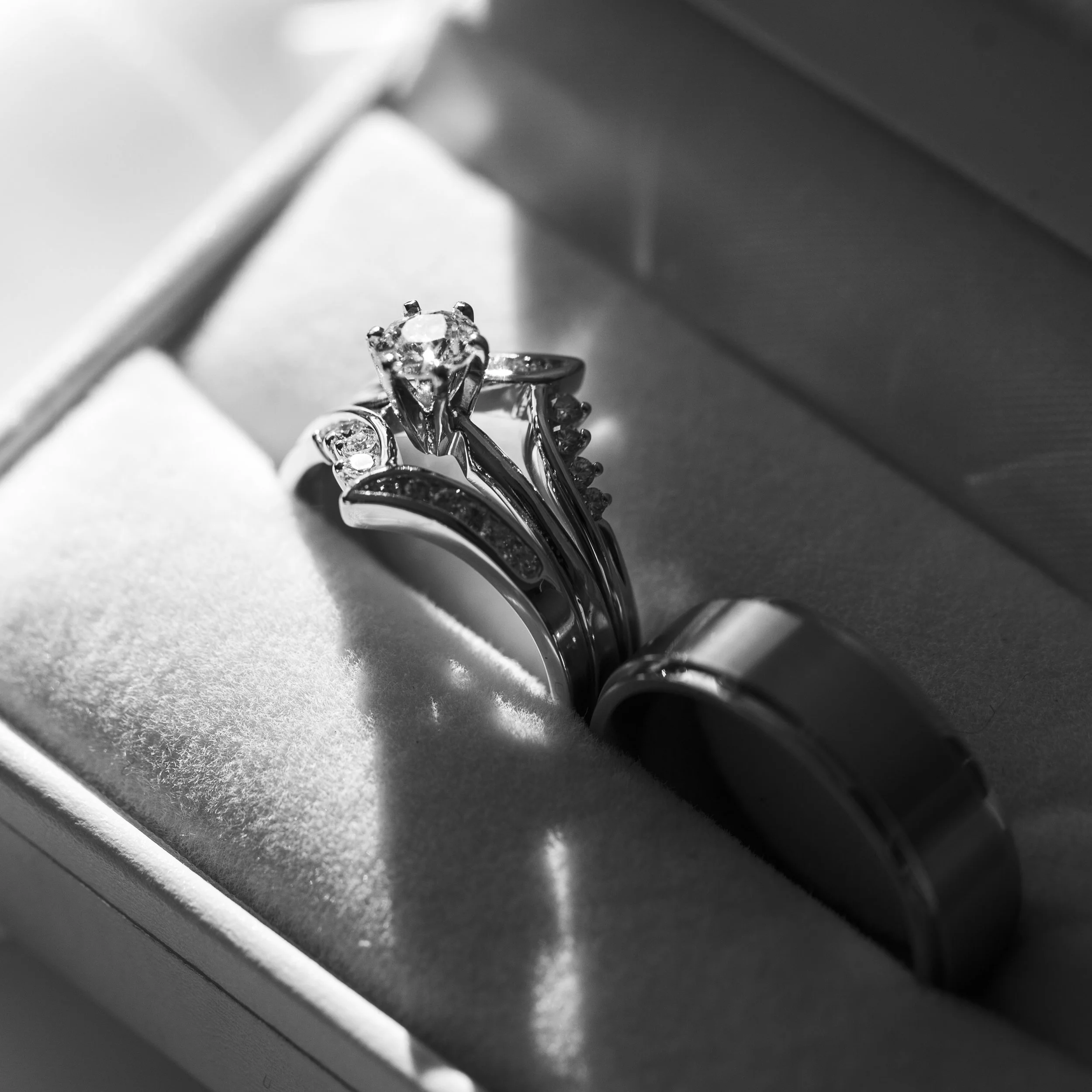 Close-up of a set of wedding rings, including a diamond engagement ring and matching wedding band, inside a jewelry box.
