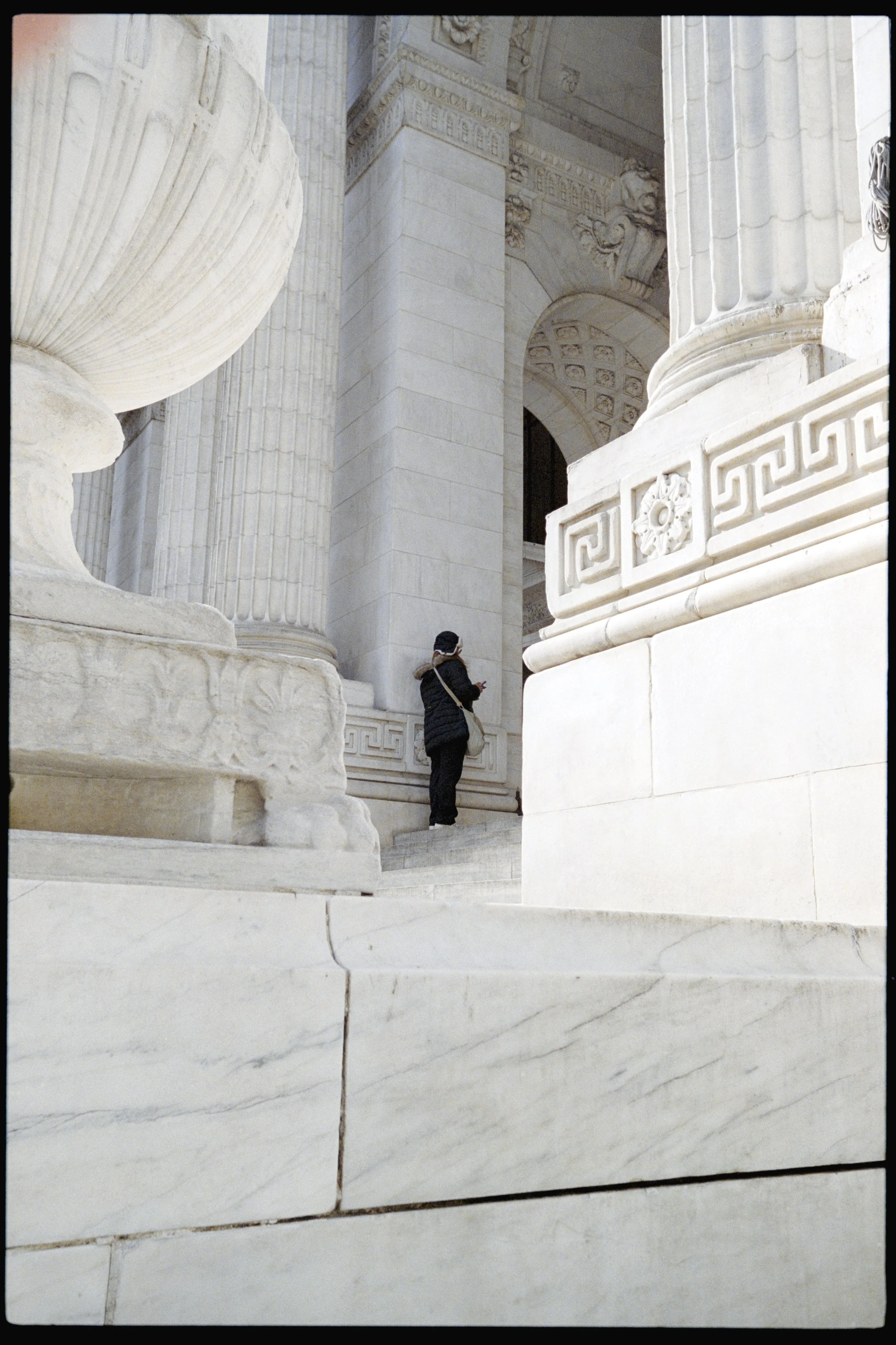 A person standing in front of large white marble columns and architectural details of a classical building, possibly a government or historical monument.
