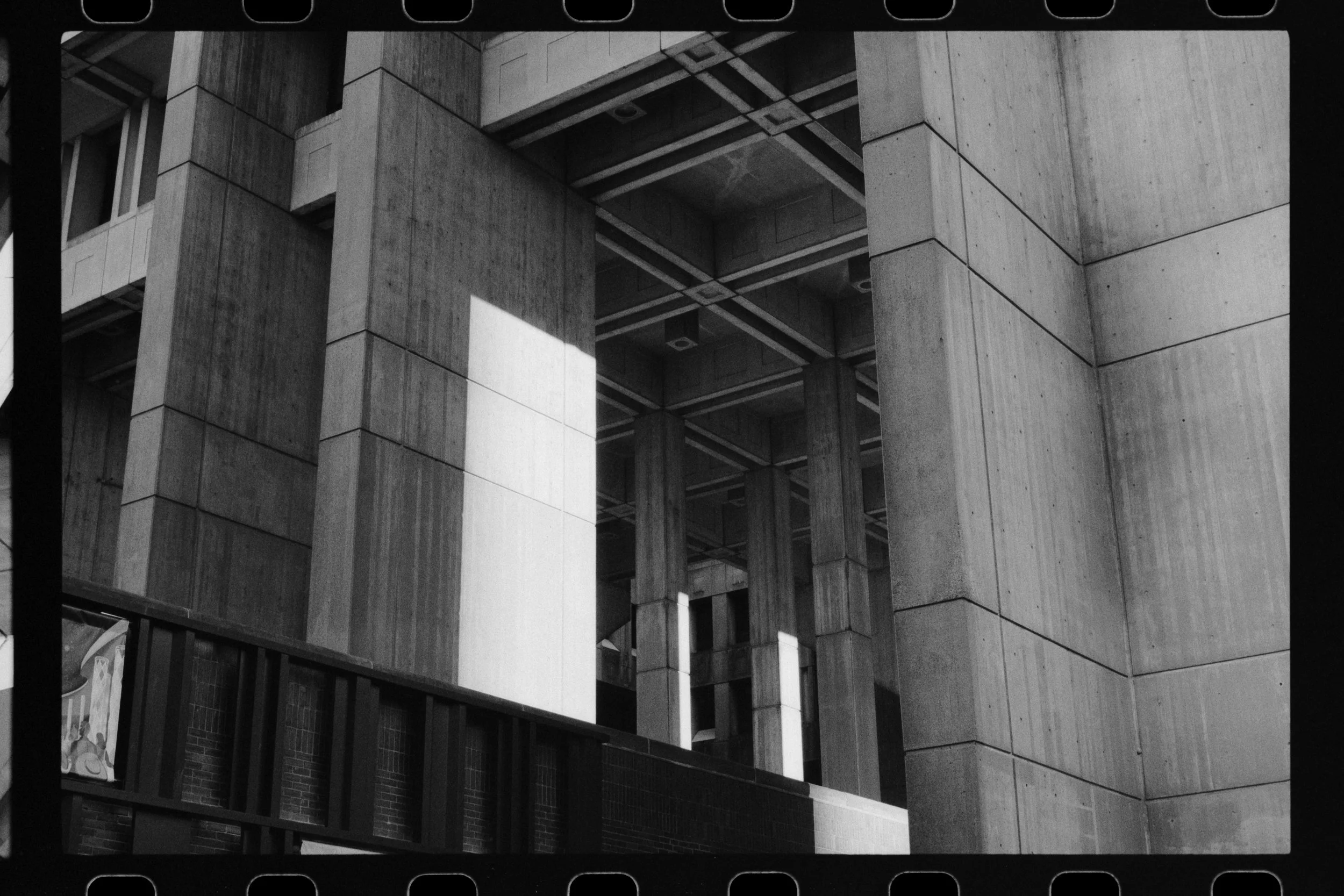 Black and white photo of a multi-level concrete building with large rectangular blocks and support columns, showcasing modern architectural design.