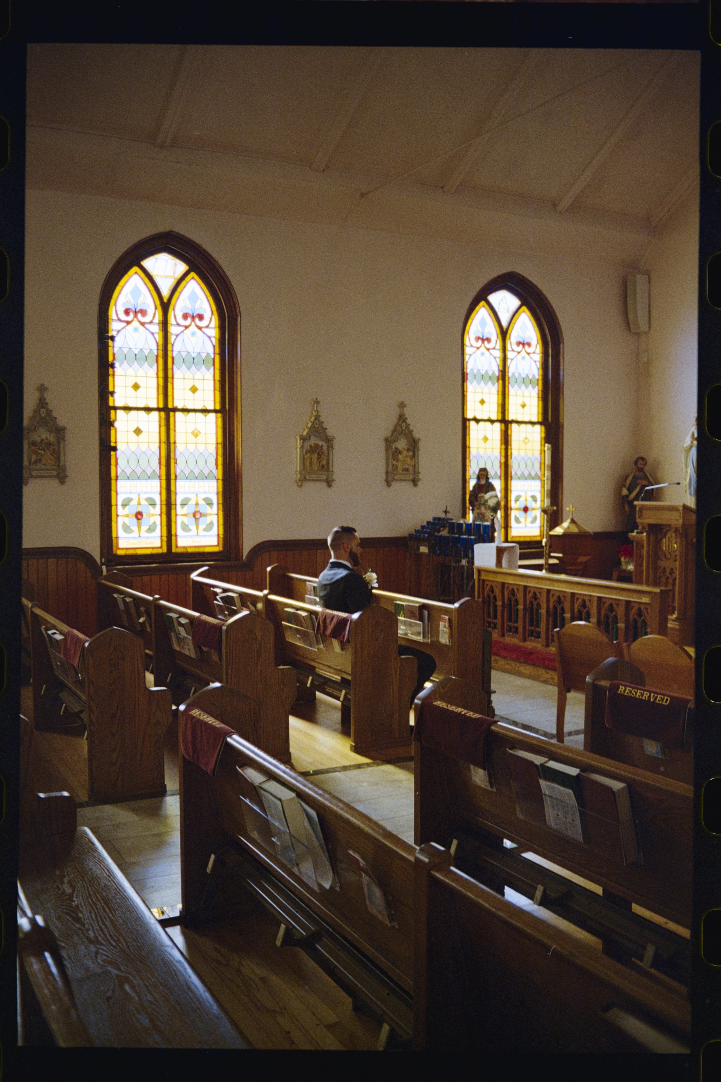Interior of a church with wooden pews, stained glass windows, and religious statues.