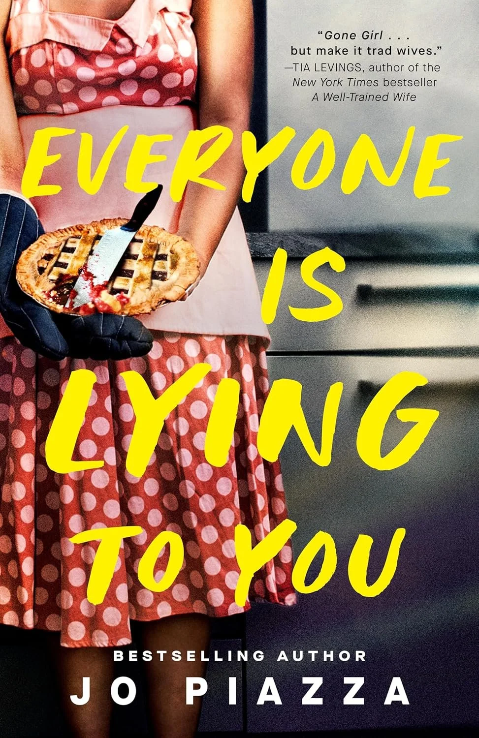 Close-up of a woman in a pink polka-dot dress and apron holding a pie with a knife, partially visible text on a book cover with the title 'Everyone is Lying to You' by Jo Piazza. The cover features a quote from Tia Levin's book and suggests themes of