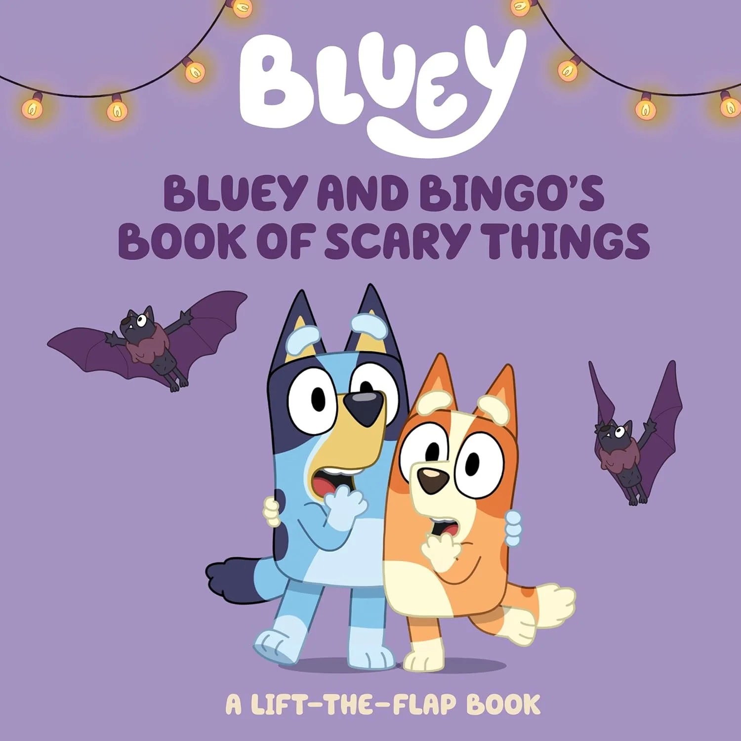 Cover of a children's book titled 'Bluey and Bingo's Book of Scary Things' featuring Bluey, an Australian Blue-Heeler puppy, and Bingo, a smaller puppy, looking frightened with wide eyes. The background is purple with hanging string lights, and two c