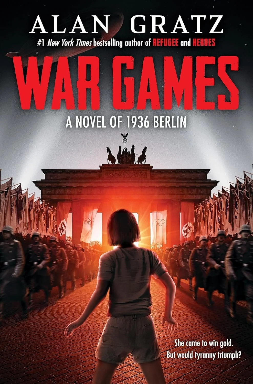 Book cover for 'War Games' by Alan Gratz, featuring a girl facing a line of soldiers in front of the Brandenburg Gate in Berlin, with a sunset or sunrise in the background.