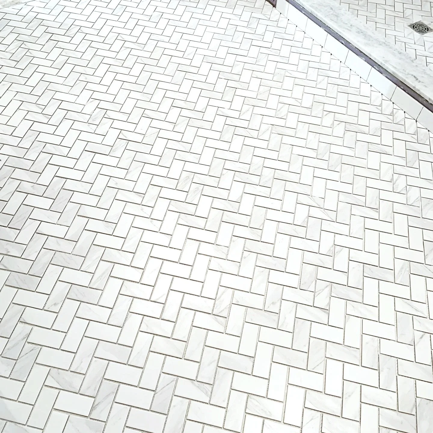 White and gray tiled floor arranged in a herringbone pattern.