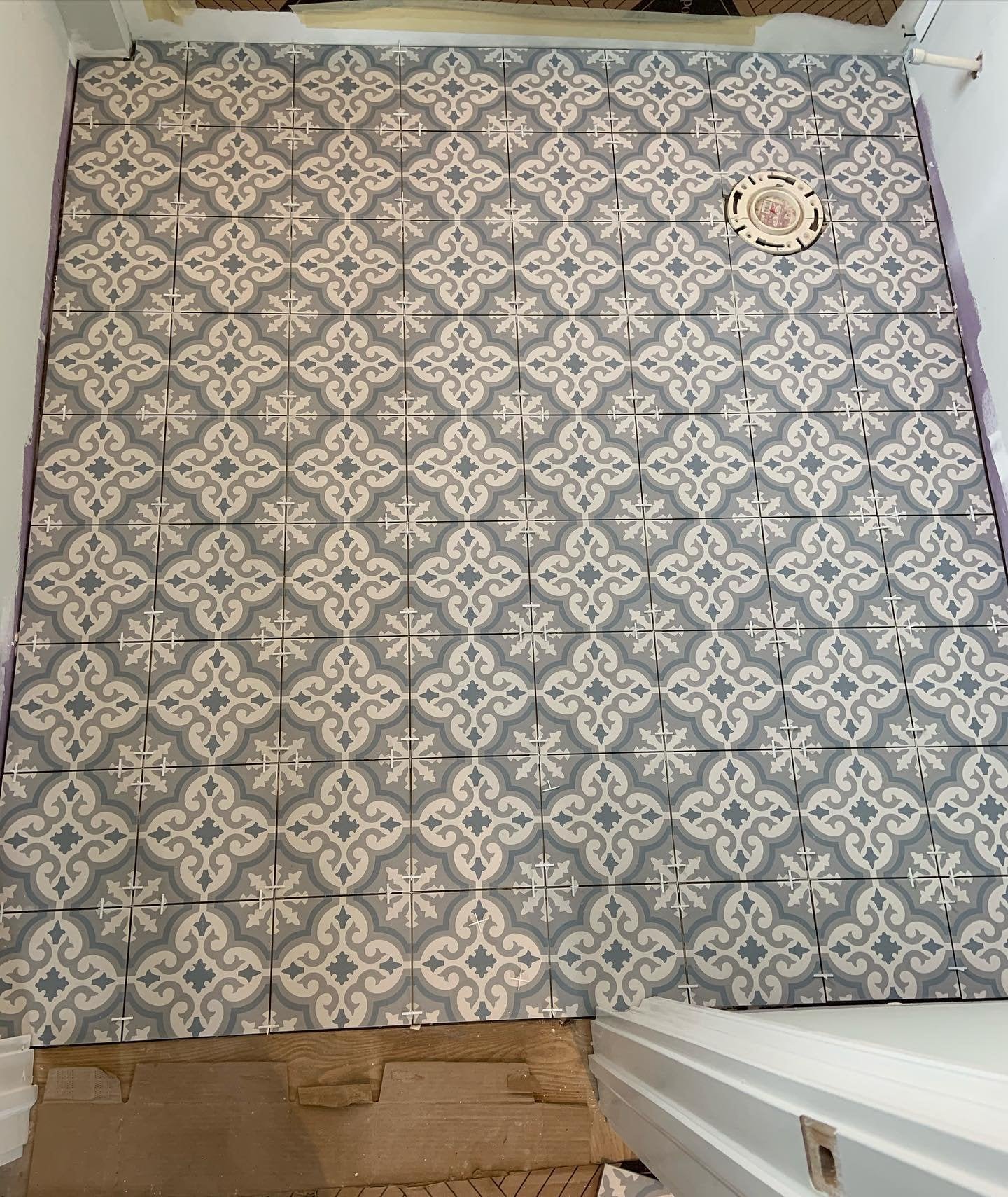 Bathroom floor with decorative gray and white patterned tiles.