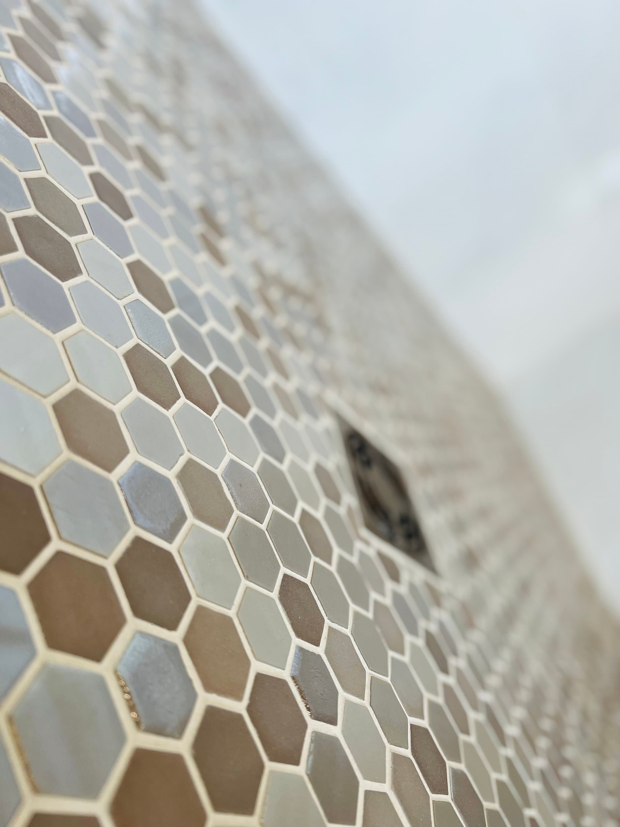 Close-up of a surface with hexagonal tiles in shades of gray and brown, with some tiles protruding slightly.