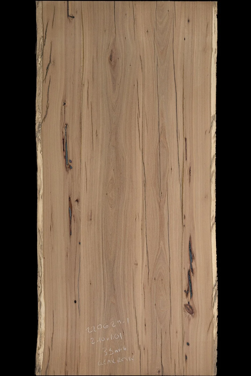 A large, rectangular piece of natural grey box hardwood with visible grain patterns and small knots. There is handwritten text on the lower part of the slab.