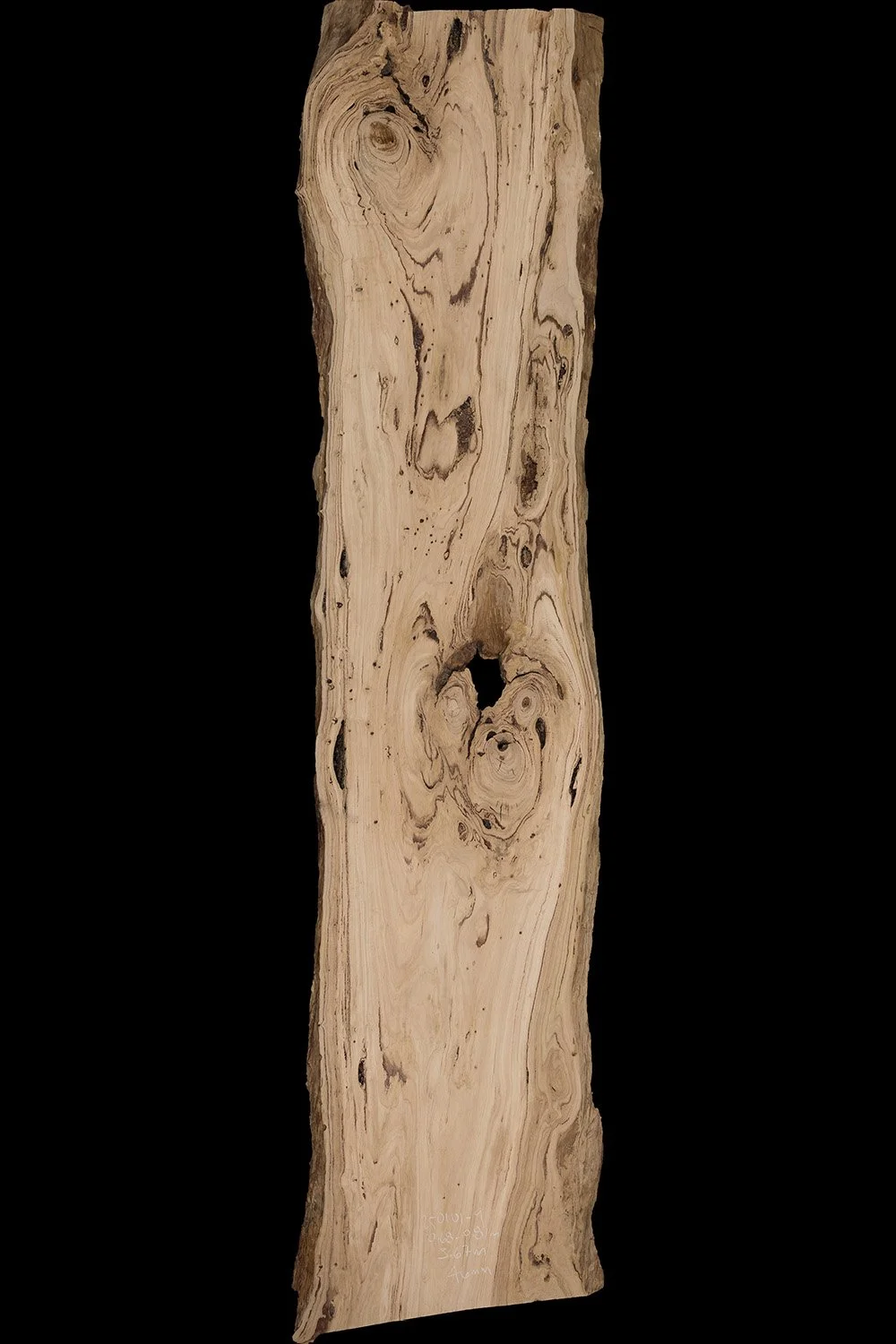 A tall, natural wooden slab with a wavy surface and visible wood grain, knots, and cracks.