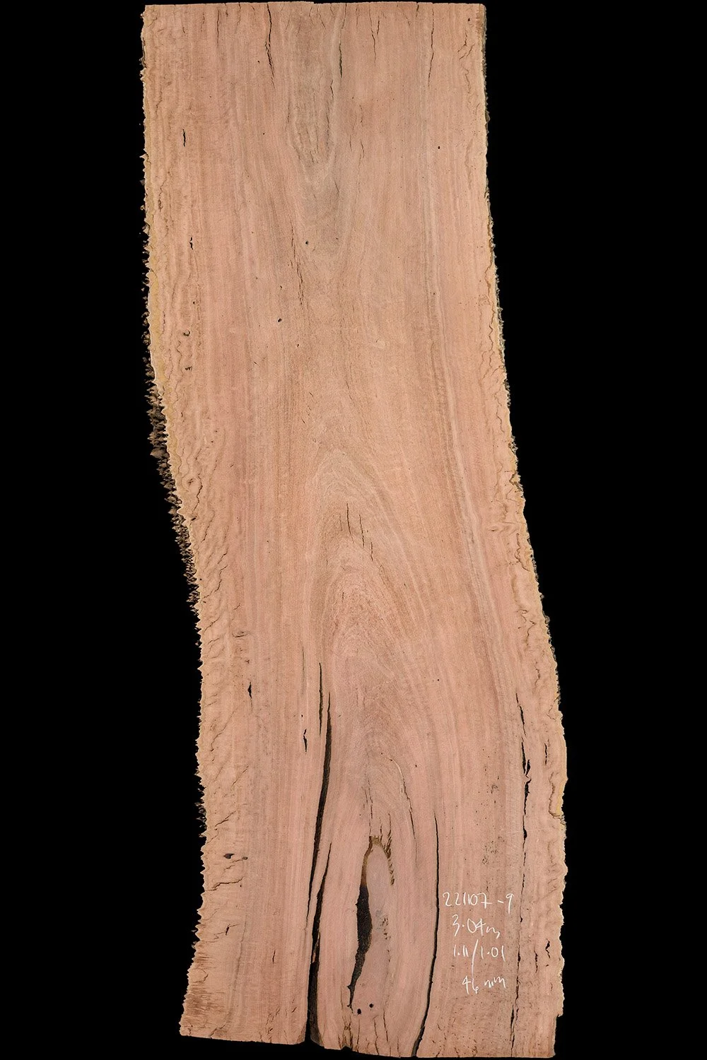 A rectangular piece of light pinkish wood with natural grain and cracks, marked with white handwriting on the bottom right corner.