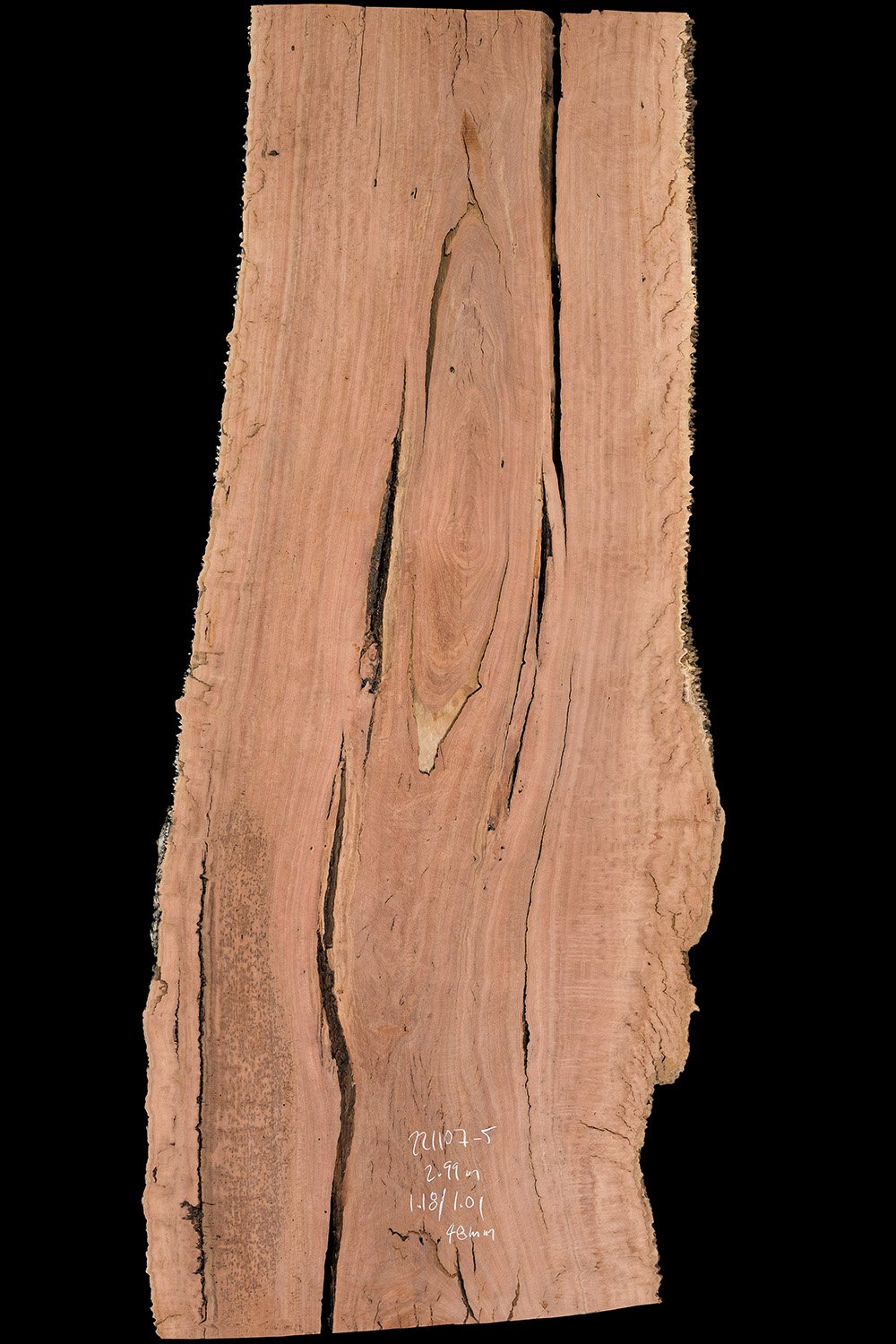 A close-up of a slab of wood with visible grain and cracks, labeled with measurements and markings.