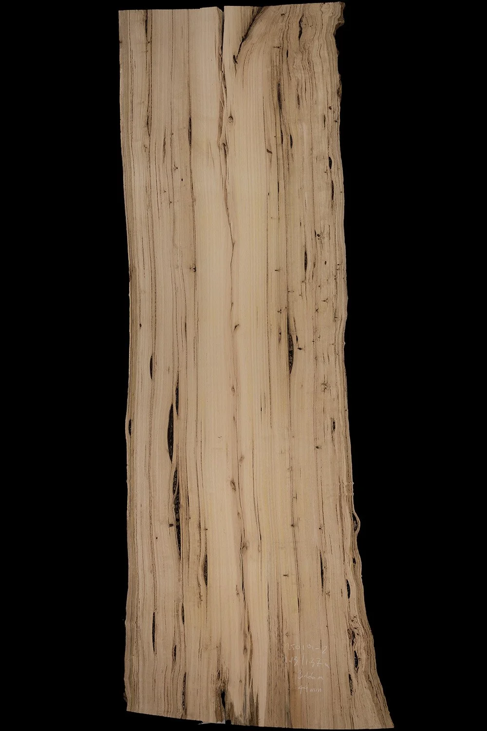 A large, vertically oriented piece of natural wood with irregular edges and visible grain patterns, set against a black background.