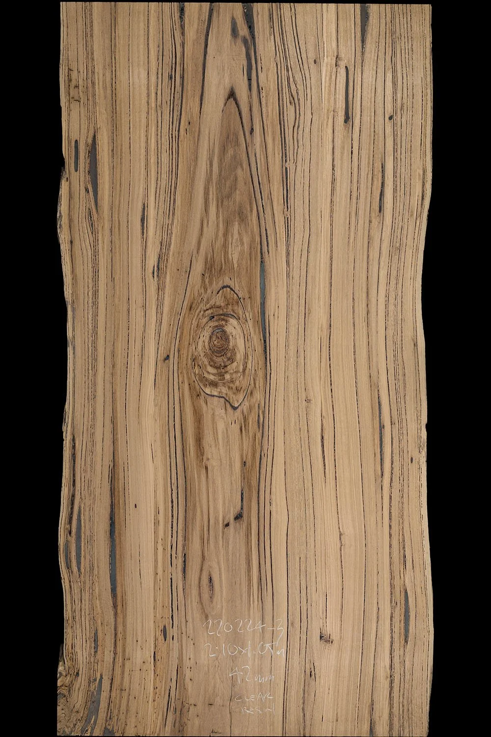 A piece of Australian hardwood with visible grain patterns, knots, and some dark streaks, with handwritten notes and measurements in white chalk or marker near the bottom.