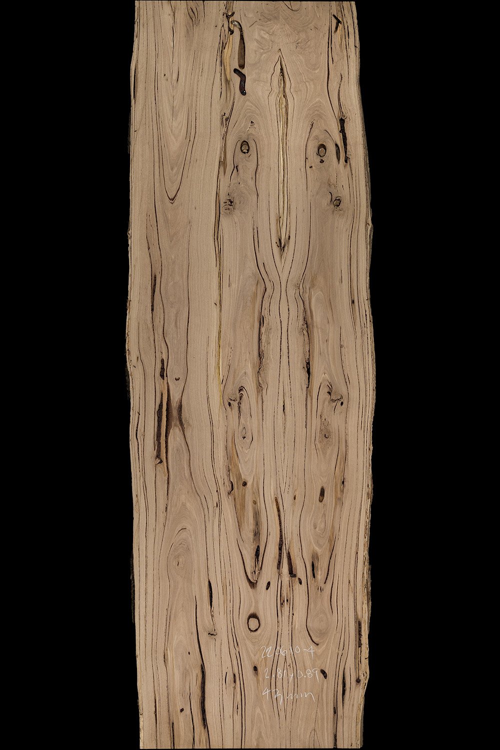 A long, narrow wooden slab with a natural, uneven edge and prominent wood grain patterns, set against a black background.