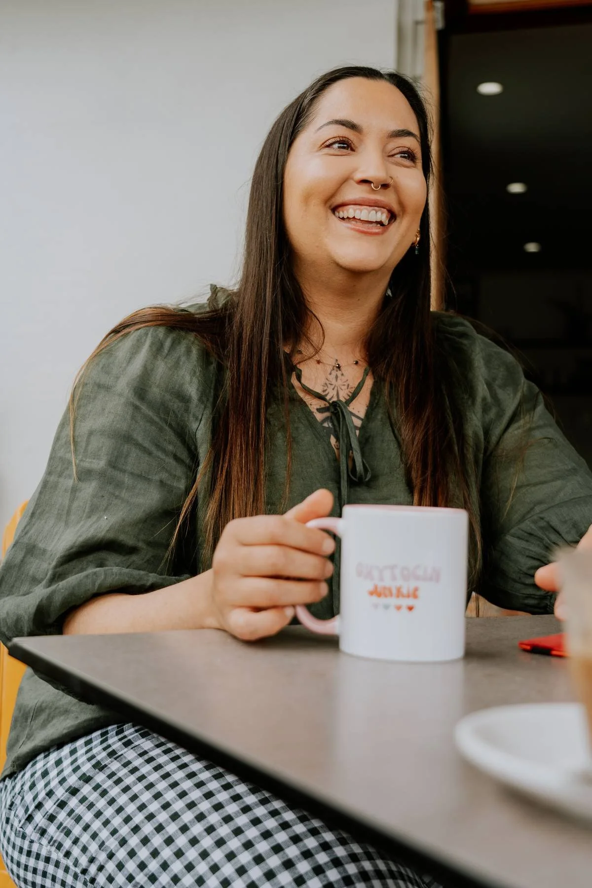 Coffs Harbour birth doula Kiran smiling over coffee with a client.