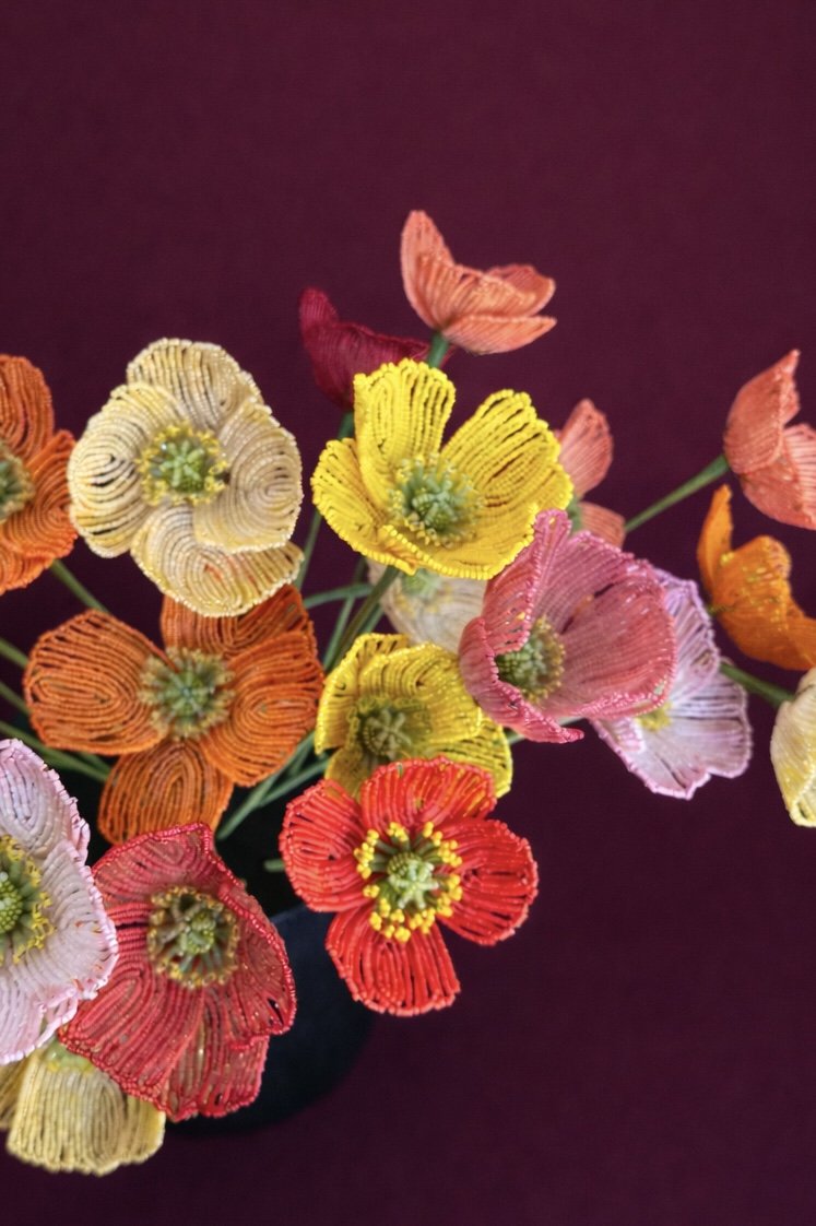 Colorful beaded flower embroidery on a dark background.