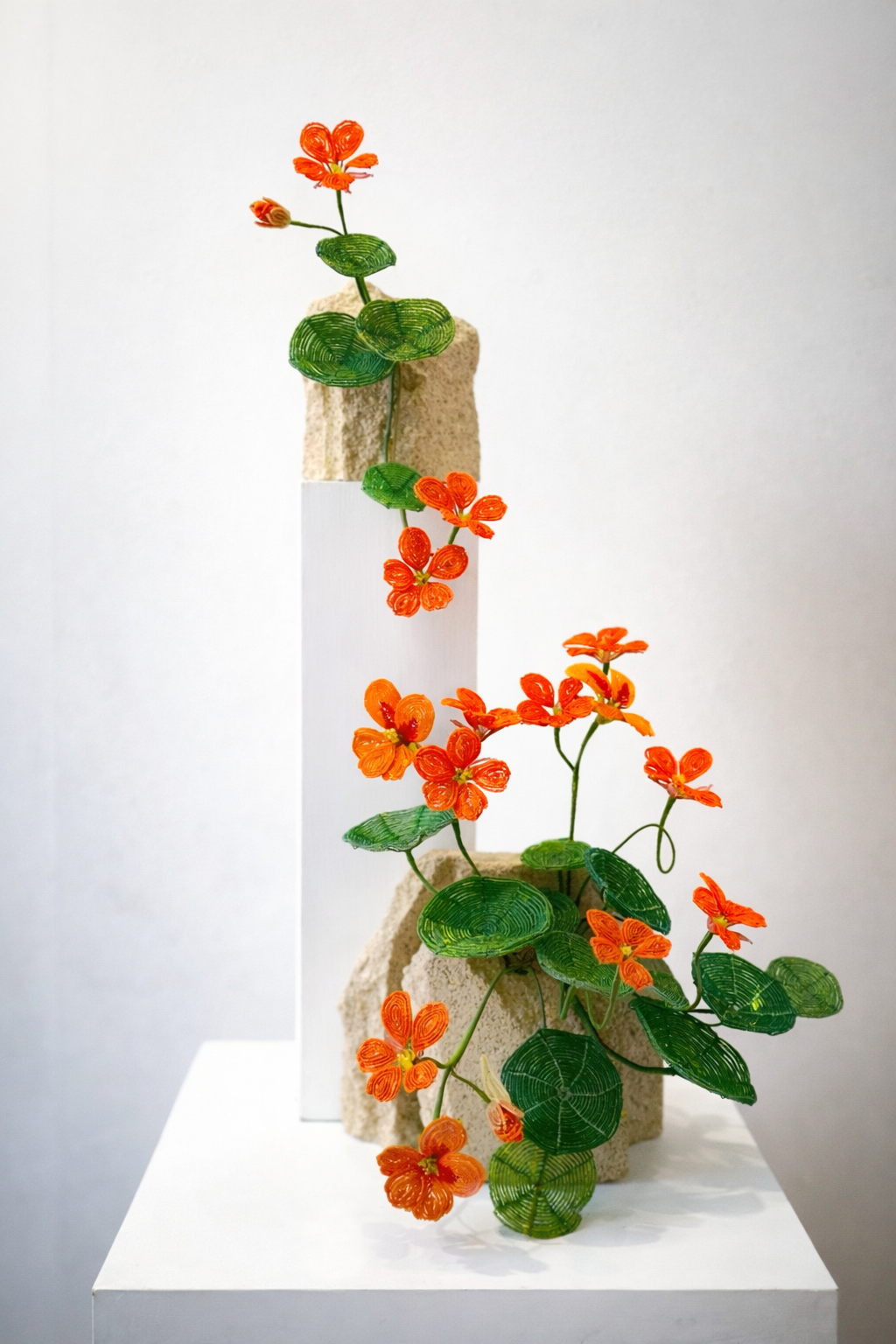 Sculpture of hand beaded orange and green nasturtium flowers on a plinth by Hark Handmade