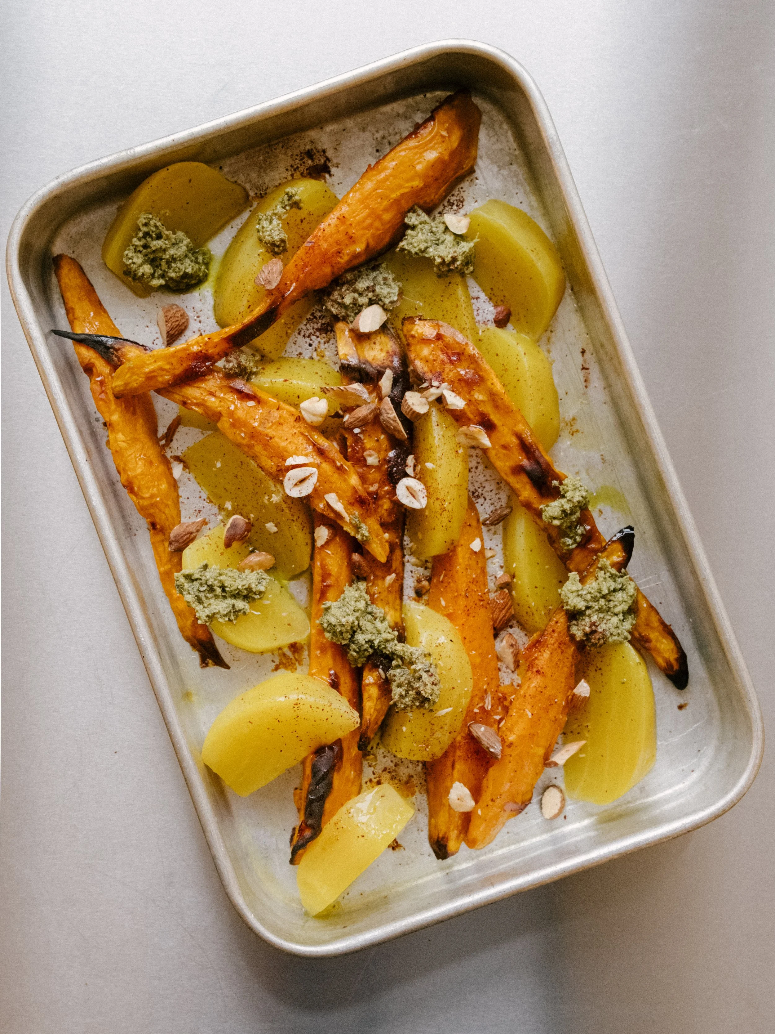 Bagte søde kartofler og gule beder toppet med pesto og sumak