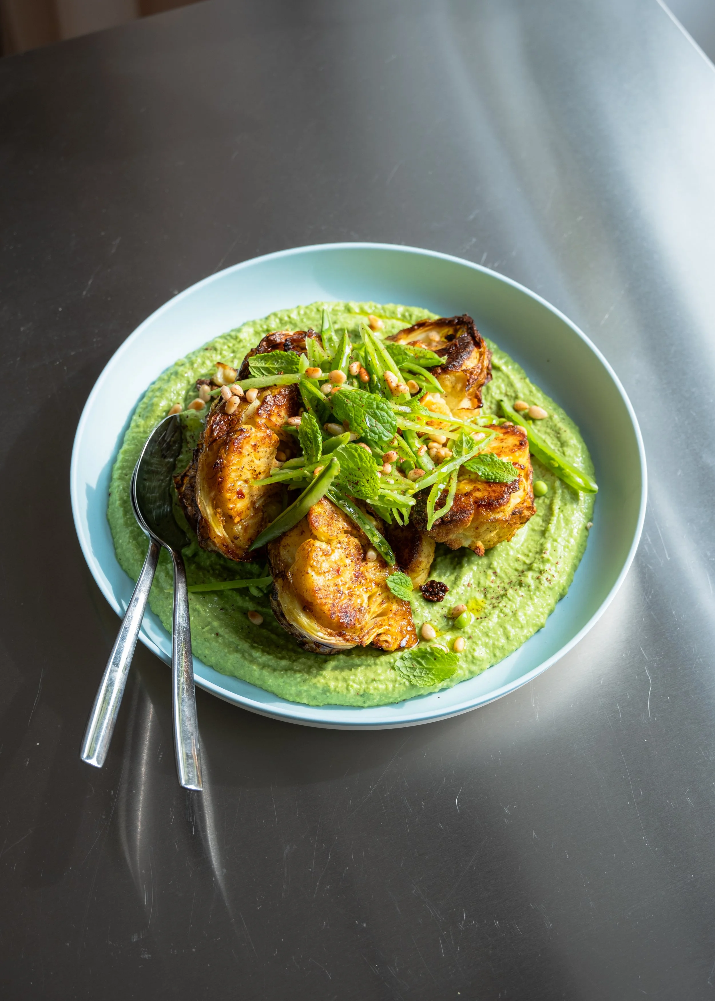 Bagt, krydret blomkål med ærtecreme, sukkerærter og ristede pinjekerner