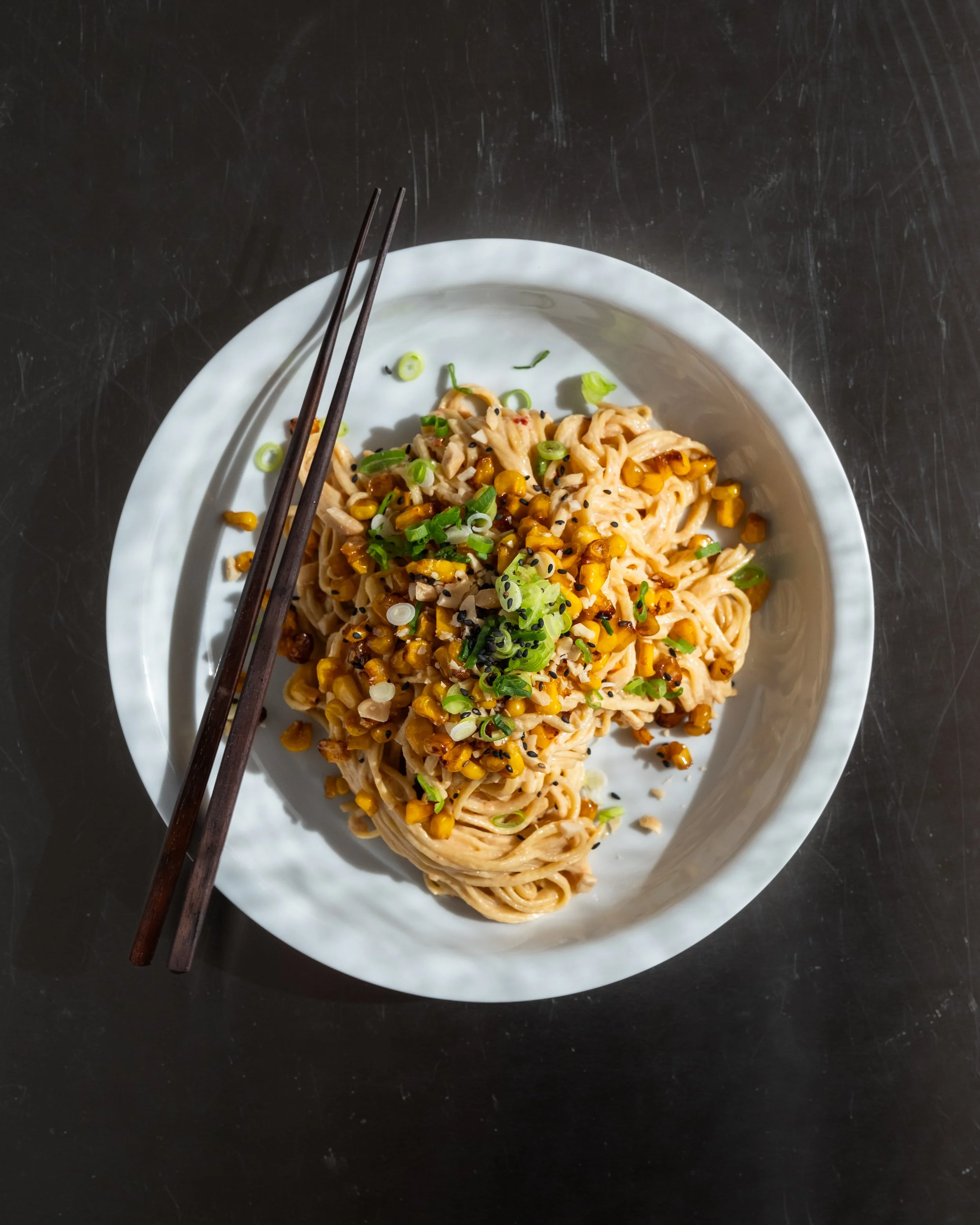Cremede peanut nudler med sprøde majs, forårsløg og sesamfrø