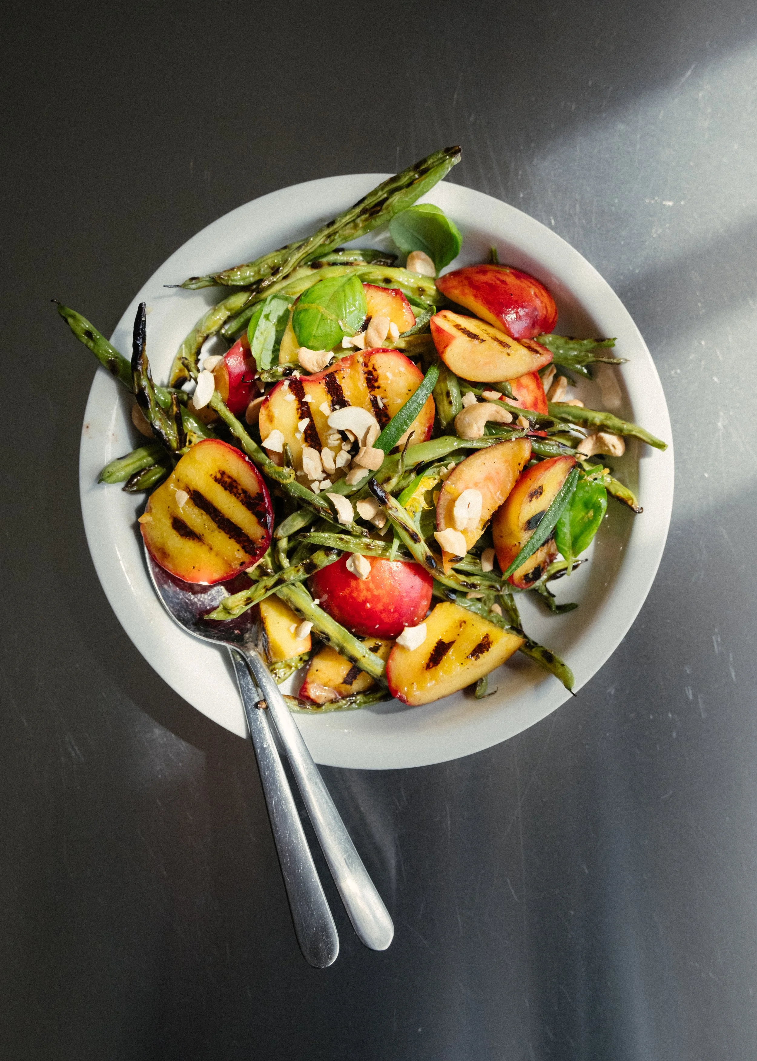Salat med grillede ferskner og friske grønne bønner, ristede cashewnødder og basilikum