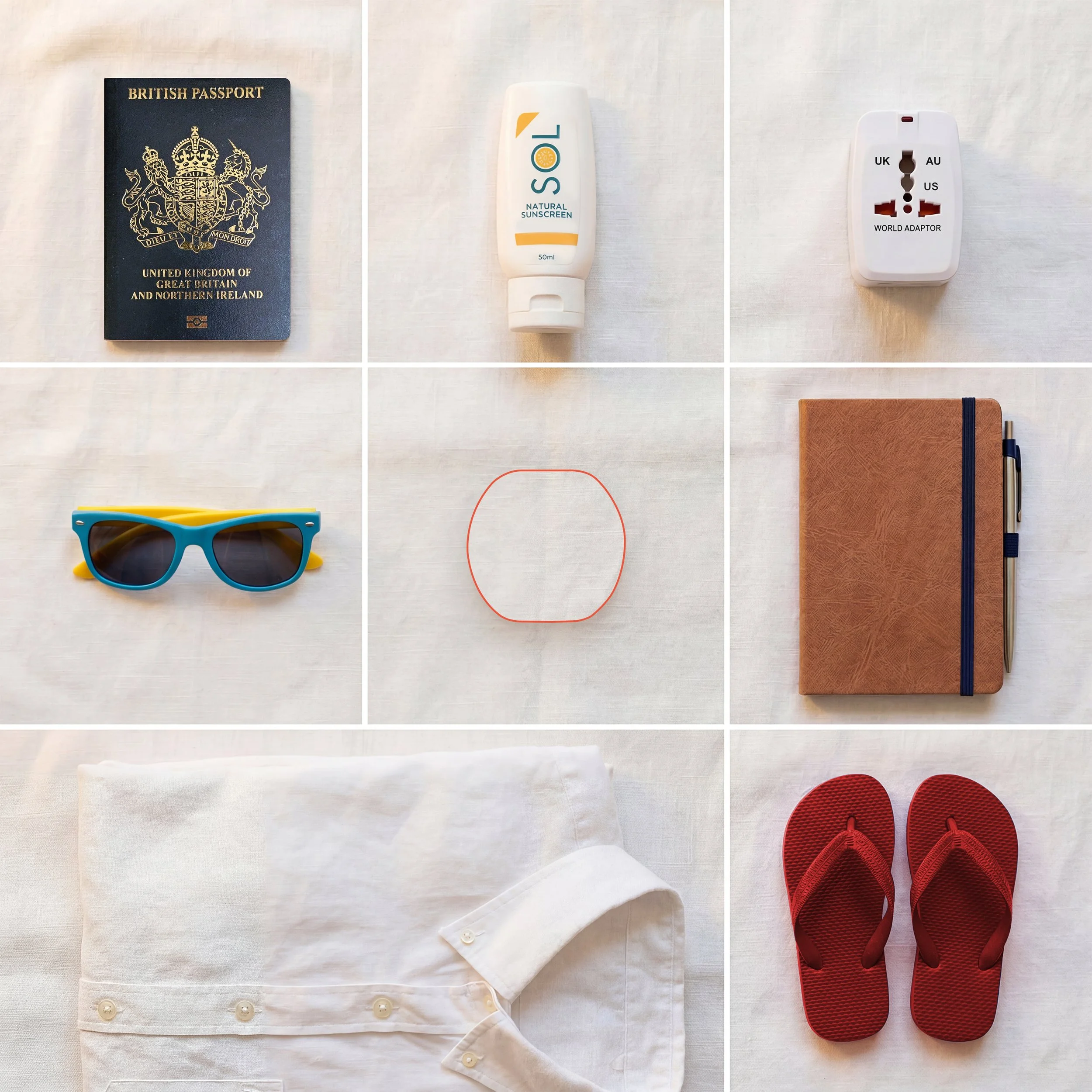A British passport, a bottle of Solar natural sunscreen, a world travel adapter, white shirt with buttons, blue and yellow sunglasses, red sneakers, brown notebook, and black pen arranged on a white surface.