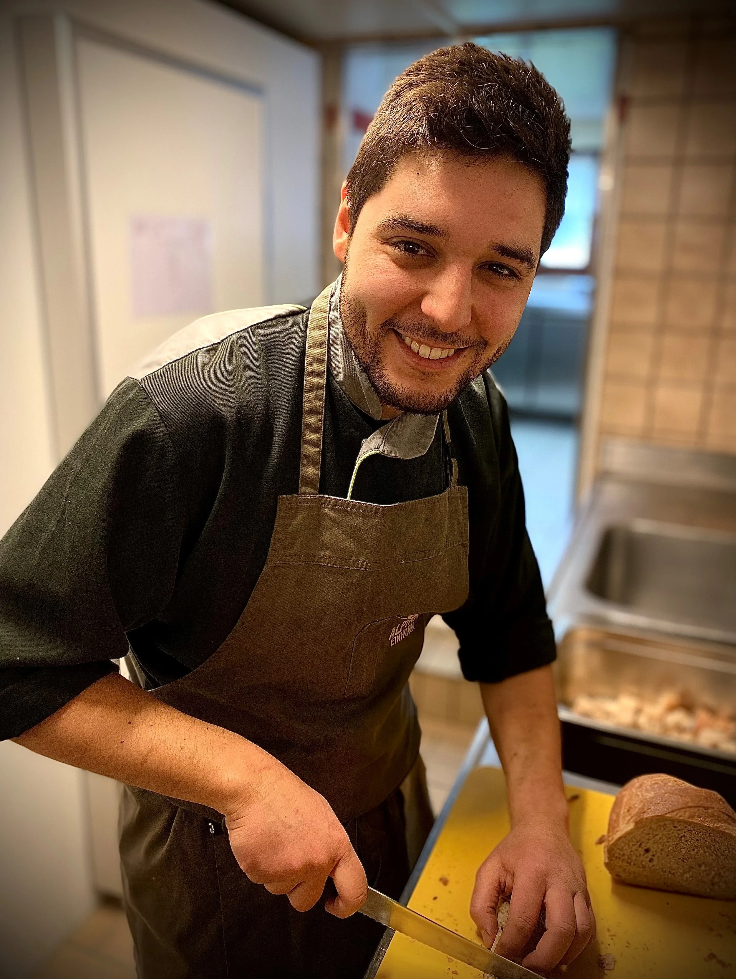 Koch in einer Küche, der Brot schneidet