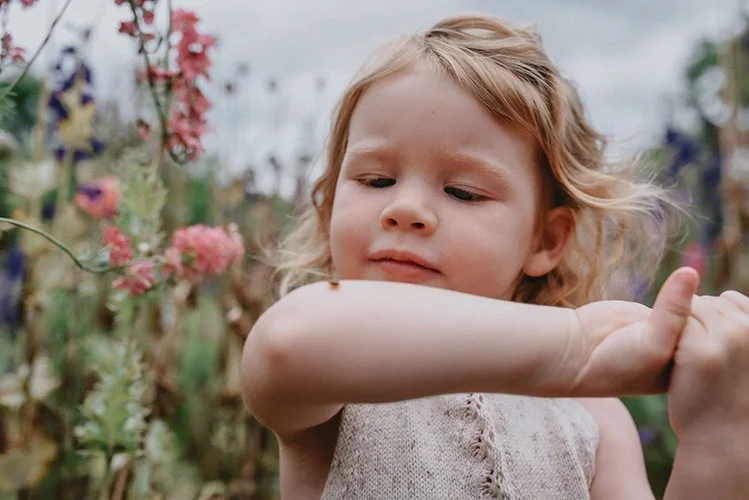 A little girl examines a bug on her arm during a family photo shoot at flying cloud farm in Asheville NC
