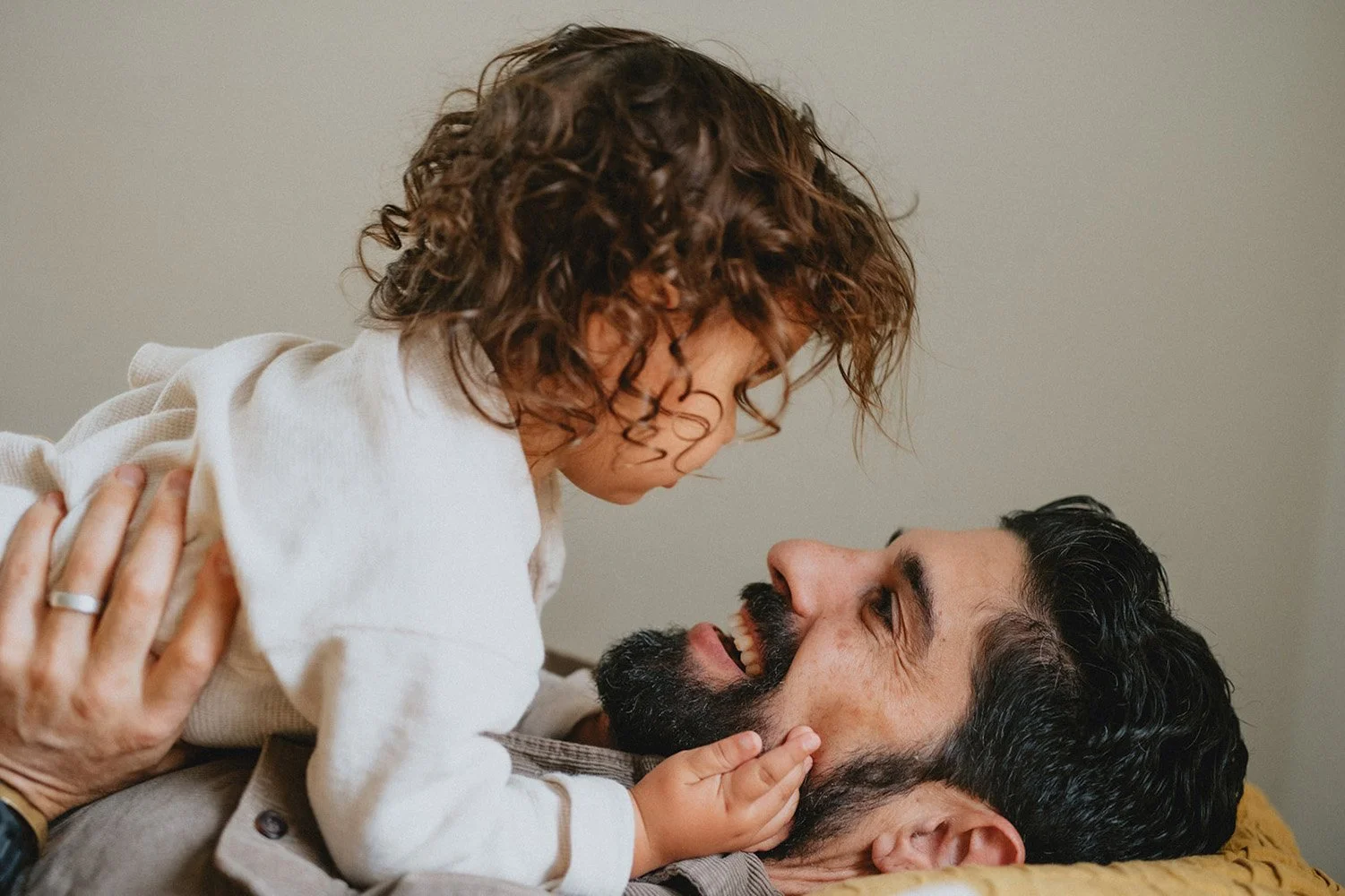 A beautiful toddler boy cuddles with his dad in a warm and cinematic family photo near Asheville North Carolina