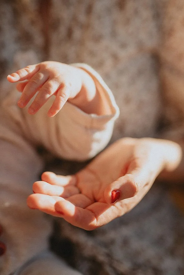 A beautiful up close, film grain images of a child and a mother's hands mirroring themselves, holding onto light during an in-home family photography session in North Carolina.