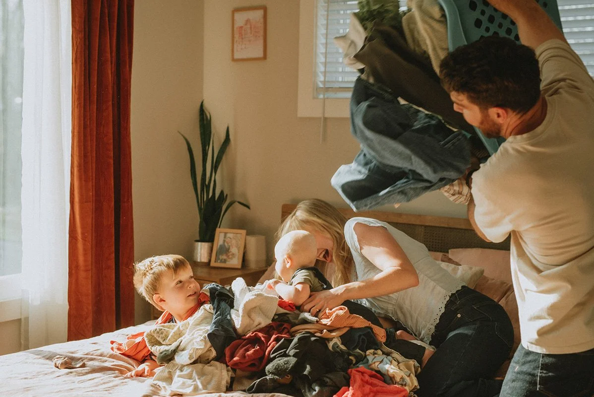 a family is doing laundry on their bed with a baby and a toddler in Asheville North Carolina