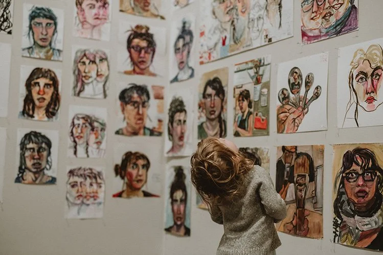 A toddler lifts her head to observe the art at the asheville art museum during a family picture session