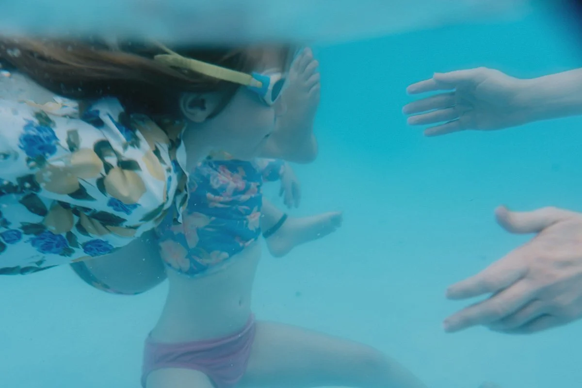 kids swim underwater. the photo was taken under water in a pool by asheville's top rated family photographer, Melina Coogan