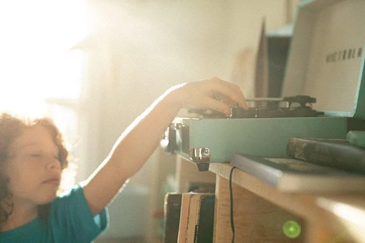 a girl shifts the needle on a record player during a family photo session in-home in Asheville.