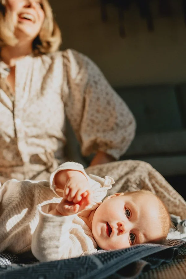 An Asheville mom and baby hang out in gorgeous heavenly light during a photo session in-home.