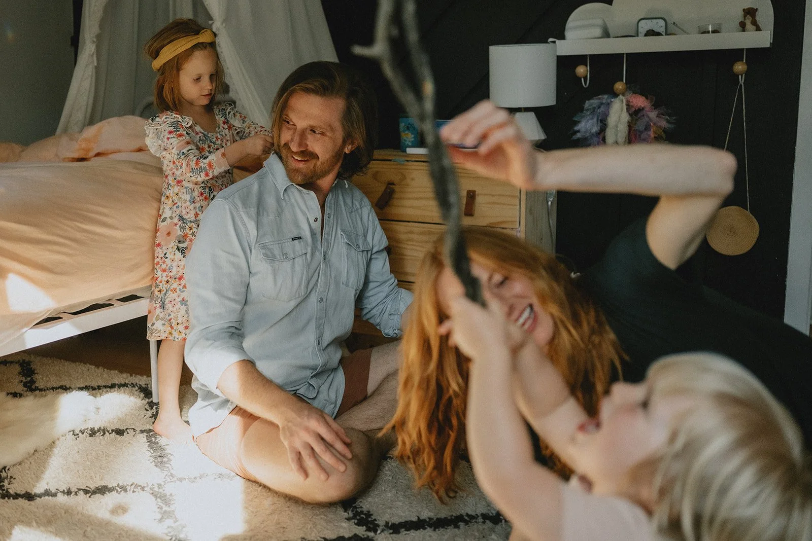 A family of four plays inside a child's bedroom in West Asheville, North Carolina during a family photo shoot. The family has red and blonde hair,