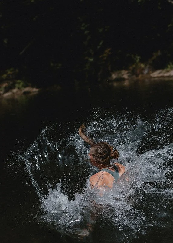 a woman jumps into the water in Brevard, North Carolina during a family photo session with Melina Coogan, Asheville's top rated family photographer