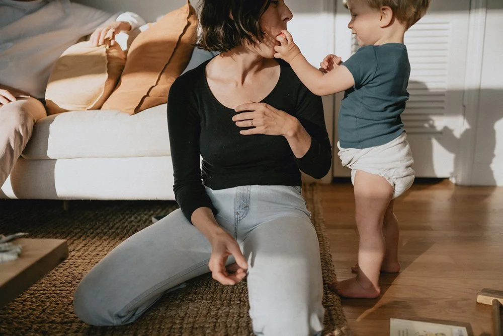 a toddler boy wearing a cloth diaper interacts with him mom inside a beautiful spacious minimalistic home in asheville during a family photo session
