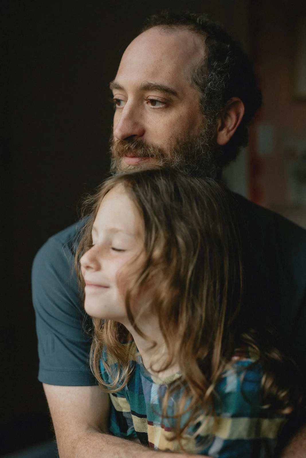 a dad and his seven year old daughter gaze out the window during a family photo shoot in North Carolina