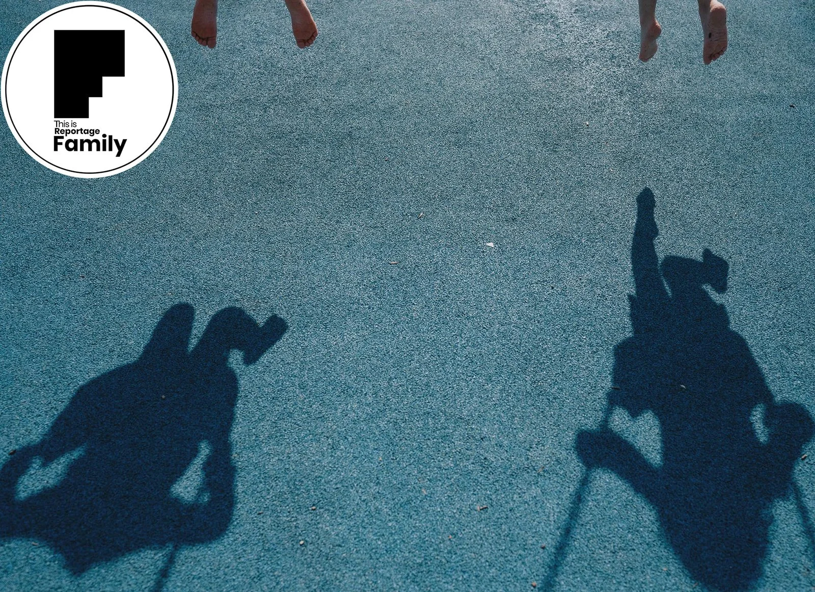 Shadows of two children riding horses on a playground surface, with the children and horses visible in the shadows.