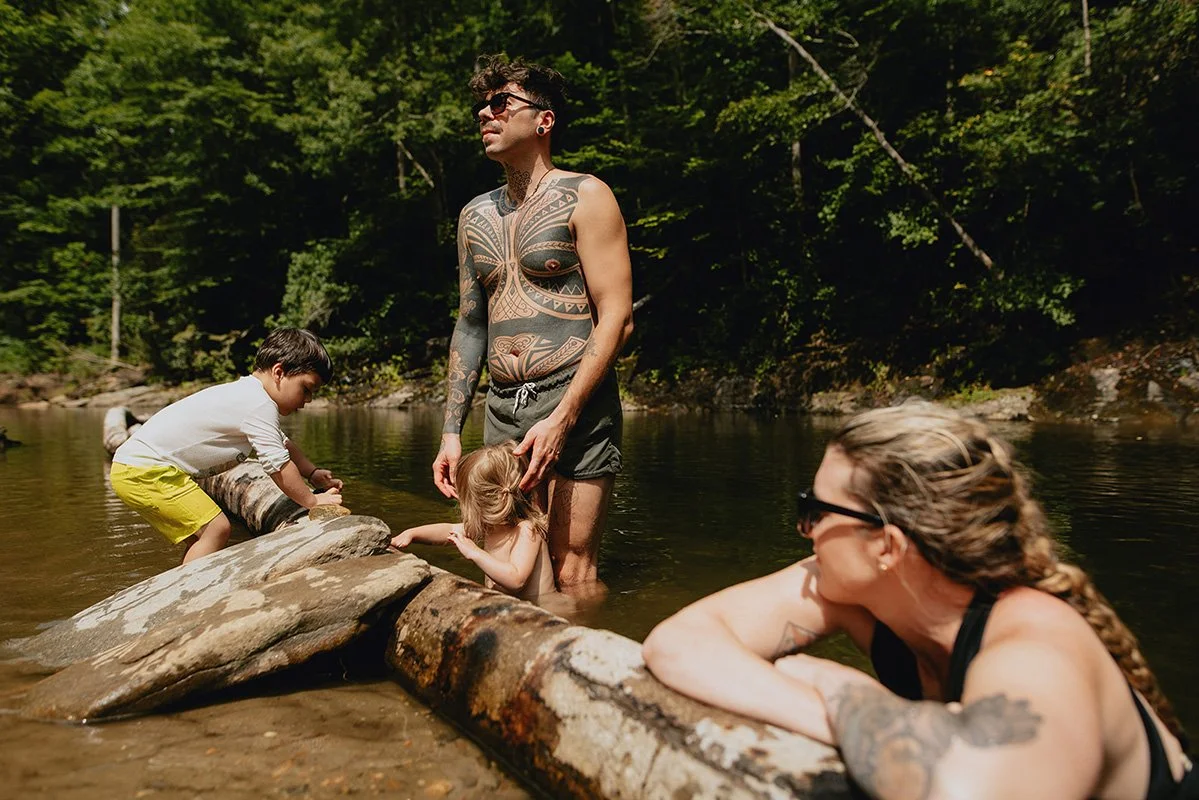 a group of friends hang out by the river in Brevard, North Carolina as the world's best family photographer takes their picture